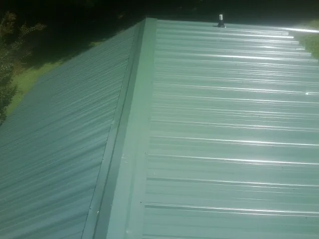 New green metal panels meeting at the ridge of a roof — Flat Roof Repair work by our crew in Montclair