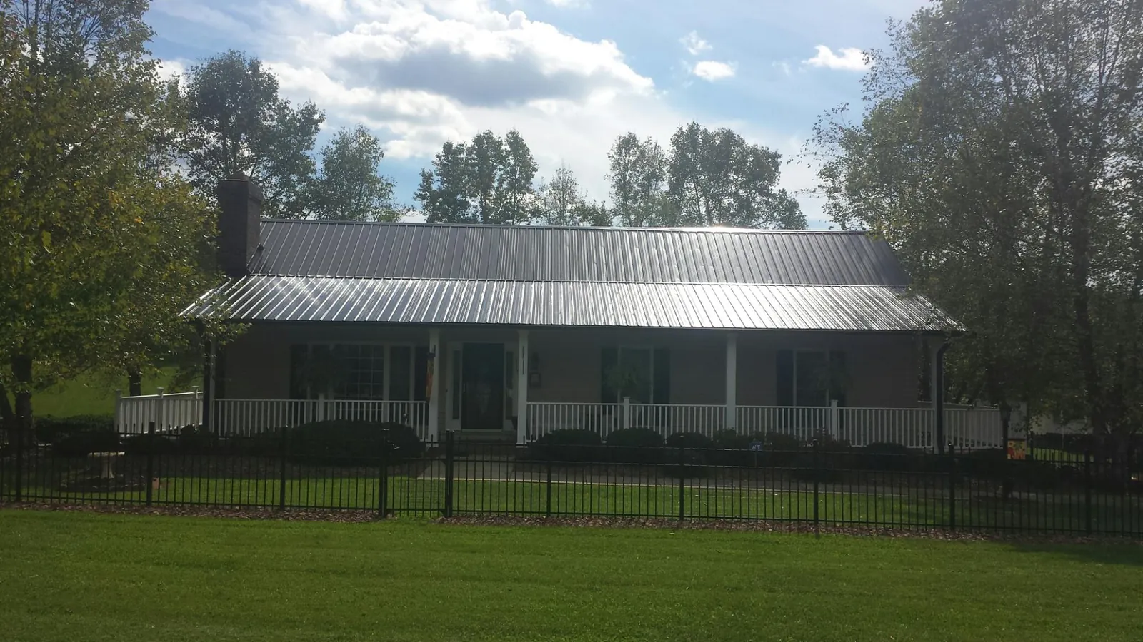 Gray metal roof on a brick ranch with a full width front porch — Gutter Guard Installation work by our crew in Montclair