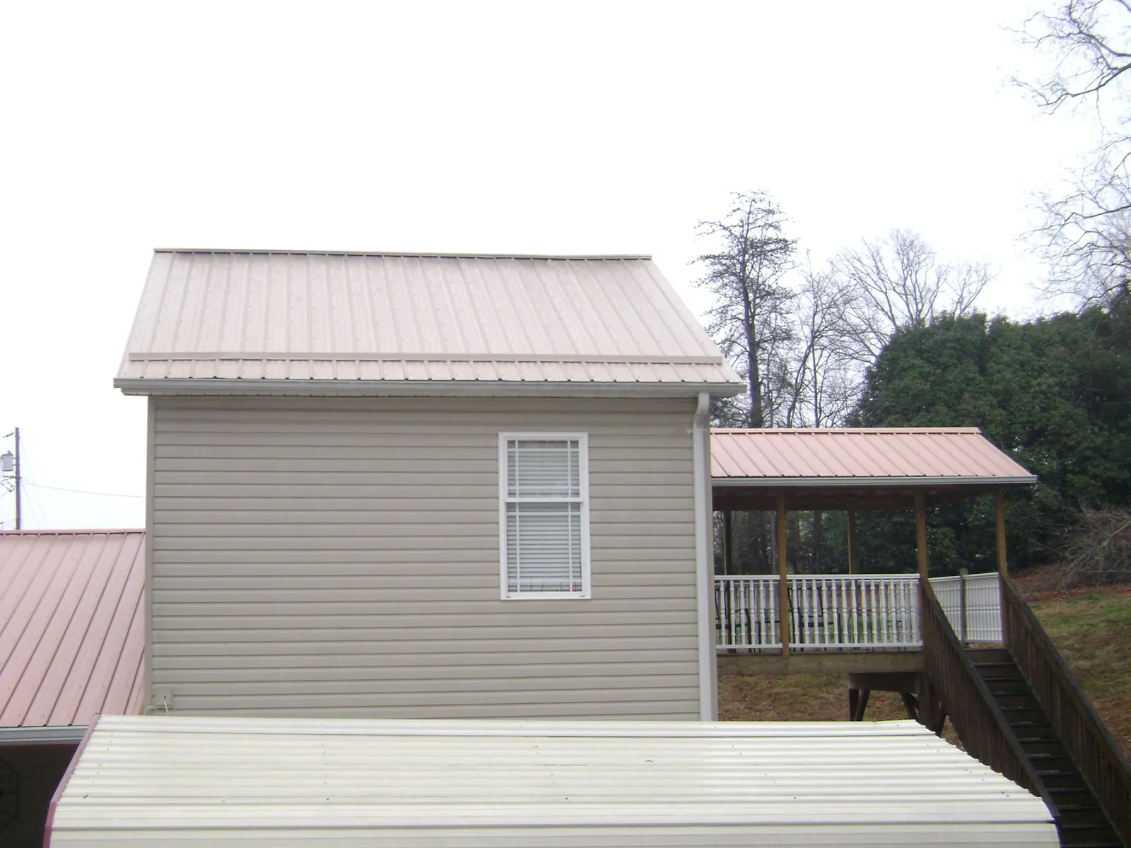 Tan metal roofs on a two story addition and attached porch, from a Roof Replacement job in Montclair